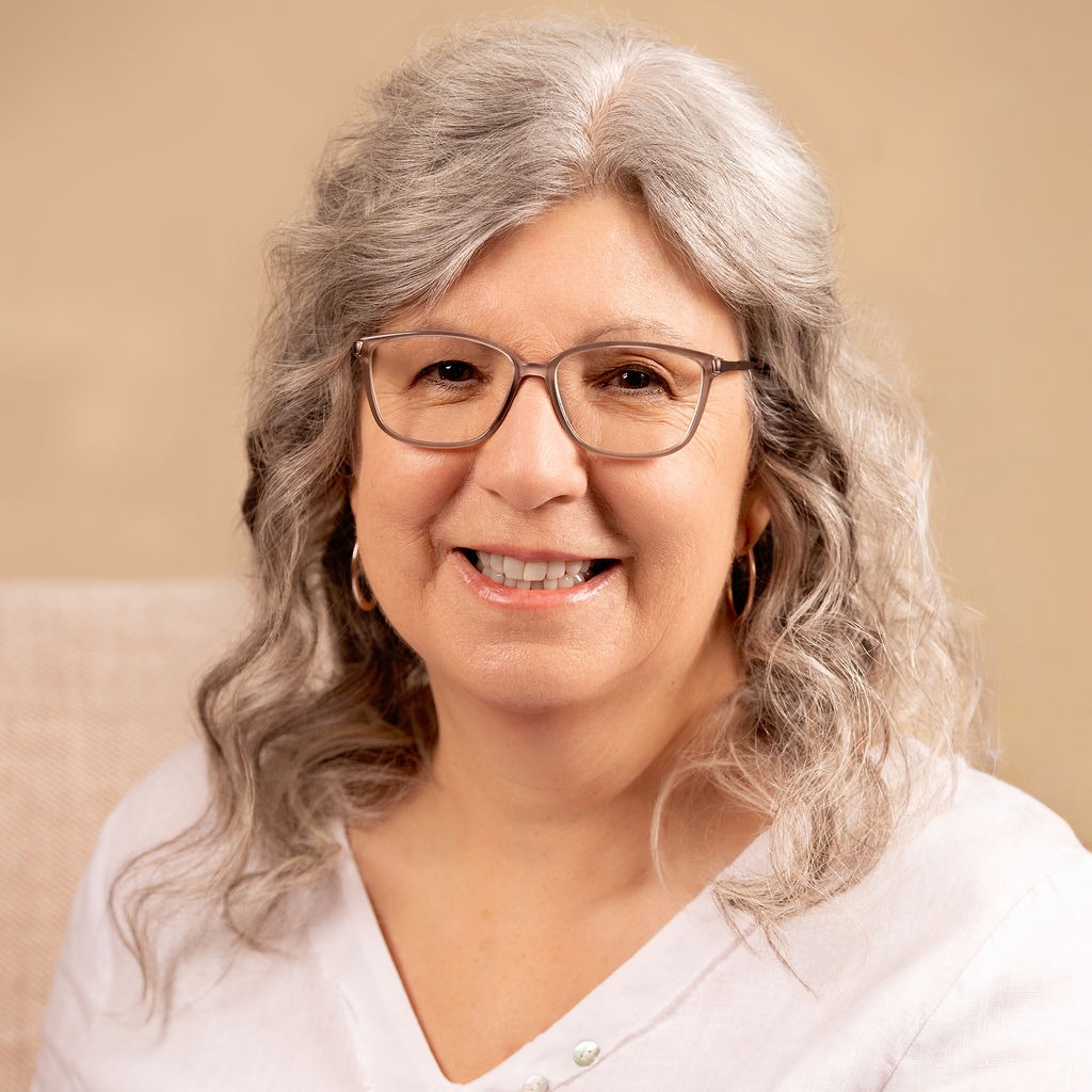 Woman with wavy hair, neutral background.